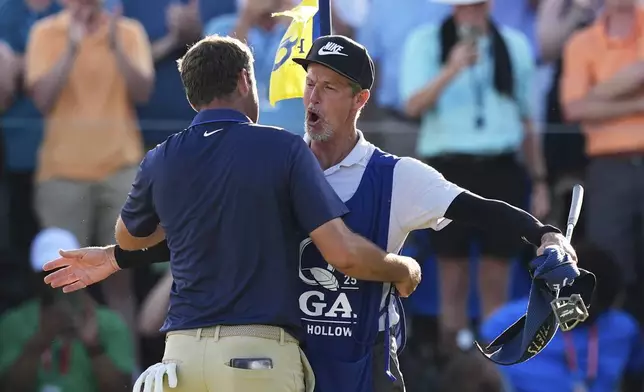 Scottie Scheffler hugs his caddie Ted Scott after winning the PGA Championship golf tournament at the Quail Hollow Club, Sunday, May 18, 2025, in Charlotte, N.C. (AP Photo/David J. Phillip)