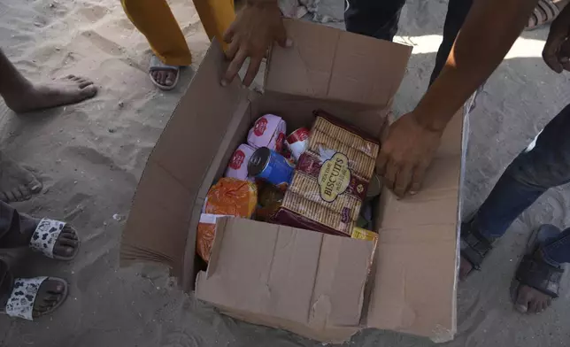 Palestinians open a box containing food and humanitarian aid packages delivered by the Gaza Humanitarian Foundation, a U.S.-backed organization approved by Israel, in Rafah, southern Gaza Strip, on Tuesday, May 27, 2025. (AP Photo/Abdel Kareem Hana)