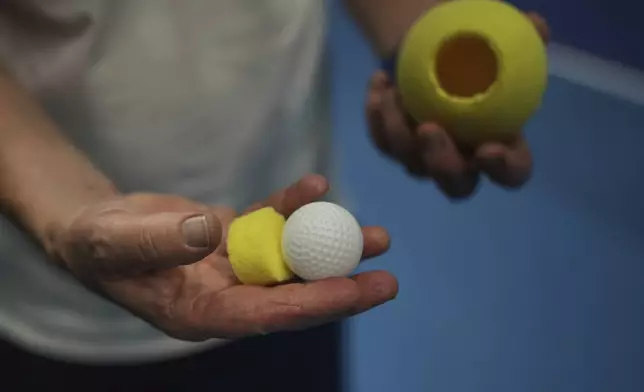 Tennis coach, Lee Neale, shows a ball used for visually impaired tennis during a training session in London, Wednesday, May 14, 2025. (AP Photo/Kin Cheung)