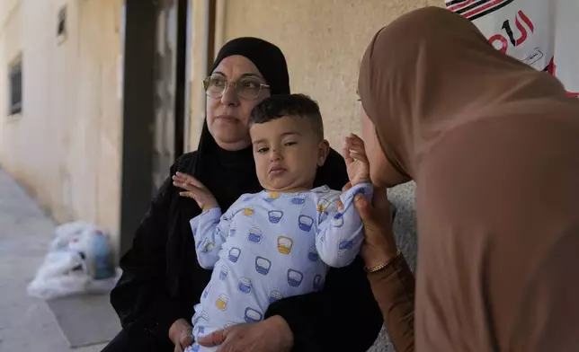 Palestinian Hazar Estity kisses her 21-month-old son, Nizar, who is being held by his grandmother, Nazek, on April 29, 2025, at an apartment in the West Bank town of Zababdeh. Estity says she was used as a human shield by Israeli soldiers. (AP Photo/Nasser Nasser)