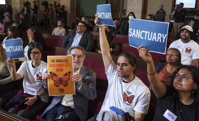 FILE - Members of immigration advocacy groups react as Los Angeles City Council votes to enact an ordinance to prohibit city resources from being used for immigration enforcement in anticipation of potential mass deportations under President-elect Donald Trump, inside Los Angeles City Hall on Tuesday, Nov. 19, 2024. (AP Photo/Damian Dovarganes, File)