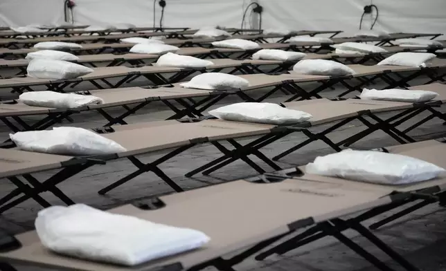 FILE - Bags containing bedding are placed on cots inside the dormitory tent during a tour of a shelter New York City is setting up to house up to 1,000 migrants, in the Queens borough of New York, Aug. 15, 2023. (AP Photo/Mary Altaffer, File)