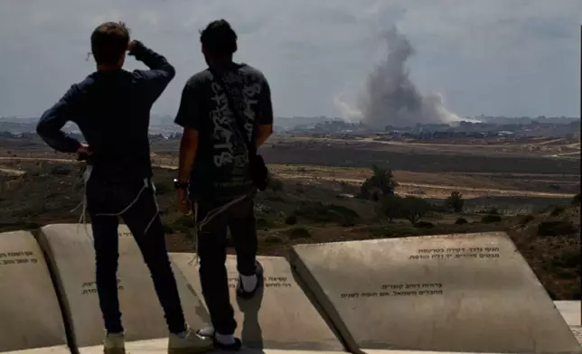 People watch smoke rising to the sky after an explosion in the Gaza Strip as they visit a sightseeing area in Sderot, southern Israel, Thursday, May 22, 2025. (AP Photo/Leo Correa)