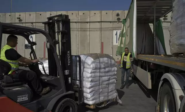 Workers unload cargo from a truck carrying humanitarian aid for the Gaza Strip at the offload area of the Kerem Shalom border crossing between Israel and Gaza, southern Israel, Thursday, May 22, 2025. (AP Photo/Leo Correa)