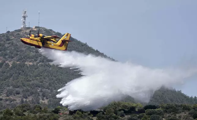 A firefighter plane drops water during the "Through Fire 2025" drill over a forest in Lavrio, about 60 kilometres (37 miles) southeast of Athens, Greece, Thursday, May 22, 2025. (AP Photo/Thanassis Stavrakis)