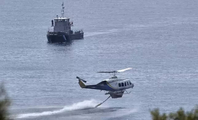 A helicopter and coast guard vessel take part in the "Through Fire 2025" drill in Lavrio, about 60 kilometres (37 miles) southeast of Athens, Greece, Thursday, May 22, 2025. (AP Photo/Thanassis Stavrakis)