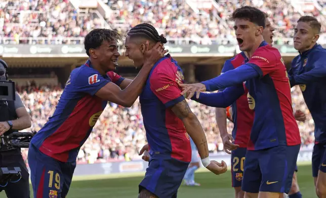 Barcelona's Raphinha, centre, celebrates with teammates after scoring his side's fourth goal during a Spanish La Liga soccer match between Barcelona and Celta de Vigo at the Lluis Companys Olympic stadium in Barcelona, Spain, Saturday, April 19, 2025. (AP Photo/Joan Monfort)