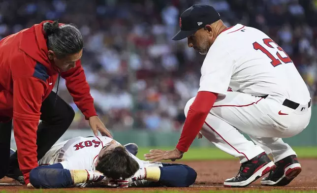 Boston Red Sox's Triston Casas lies on the field while comforted by manager Alex Cora (13) after an apparent injury during the second inning of a baseball game against the Minnesota Twins at Fenway Park, Friday, May 2, 2025, in Boston. (AP Photo/Charles Krupa)