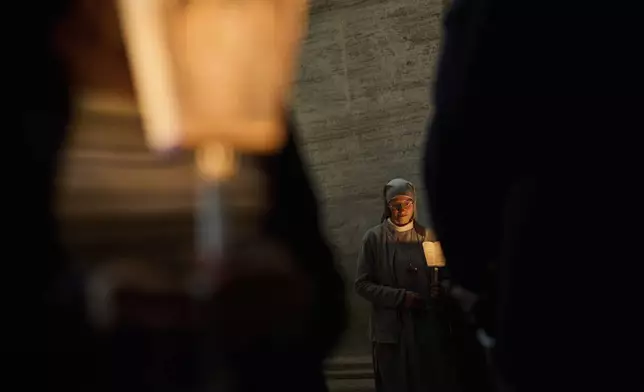 A Catholic nun attends rosary prayer and a candlelight procession with the image of Mater Ecclesiae in St. Peter's Square at the Vatican,Saturday, May 3, 2025. (AP Photo/Bernat Armangue)
