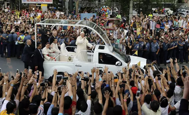 FILE - Pope Francis waves to onlookers from his popemobile as his motorcade passes by on the way to another "Meeting With Families" at the Mall of Asia Arena in Manila, Philippines, Jan. 16, 2015. (AP Photo/Bullit Marquez, File)