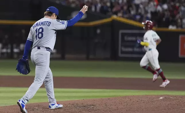 Los Angeles Dodgers starting pitcher Yoshinobu Yamamoto (18), of Japan, holds a new ball after giving up a grand slam to Arizona Diamondbacks' Gabriel Moreno, right, during the fourth inning of a baseball game Thursday, May 8, 2025, in Phoenix. (AP Photo/Ross D. Franklin)