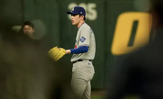 Los Angeles Dodgers pitcher Roki Sasaki warms up in the rain as ground crew removes the tarp ahead of a baseball game between the Atlanta Braves and the Los Angeles Dodgers, Saturday, May 3, 2025, in Atlanta. (AP Photo/Mike Stewart)
