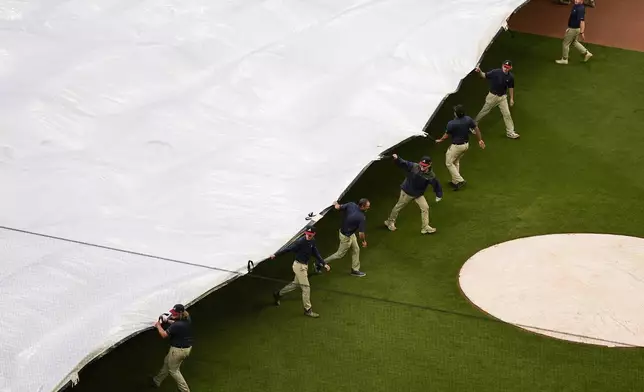 Crews cover the field before a rain-delayed baseball game between the Atlanta Braves and the Los Angeles Dodgers, Saturday, May 3, 2025, in Atlanta. (AP Photo/Mike Stewart)