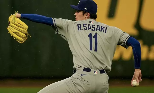 Los Angeles Dodgers pitcher Roki Sasaki warms up in the rain ahead of a baseball game between the Atlanta Braves and the Los Angeles Dodgers, Saturday, May 3, 2025, in Atlanta. (AP Photo/Mike Stewart)