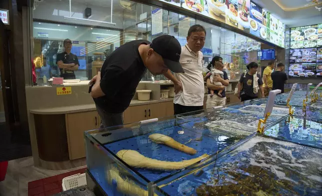 A customer looks at geoducks from Canada at a restaurant in Sanya in southern China's Hainan province on Friday, April 25, 2025. (AP Photo/Ng Han Guan)