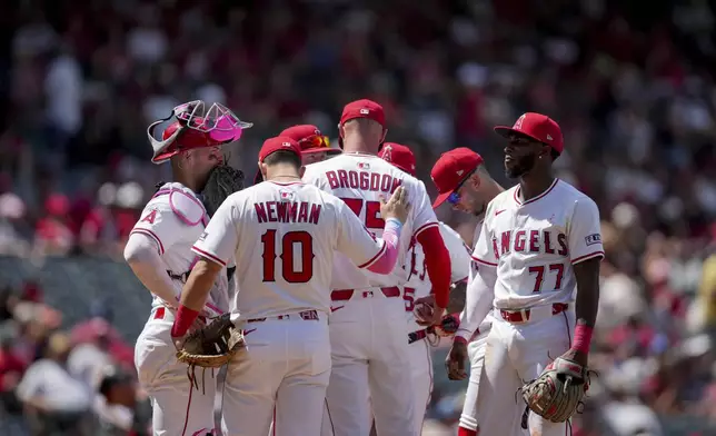 Los Angeles Angels first baseman Kevin Newman (10) pats relief pitcher Connor Brogdon (75) on the back during the sixth inning of a baseball game against the Baltimore Orioles, Sunday, May 11, 2025, in Anaheim, Calif. (AP Photo/Eric Thayer)