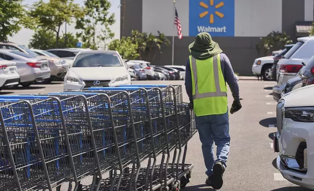 FILE - Empty shopping carts are collected from the parking lot at Walmart store in Burbank, Calif., on Thursday, April 10, 2025. (AP Photo/Damian Dovarganes, File)