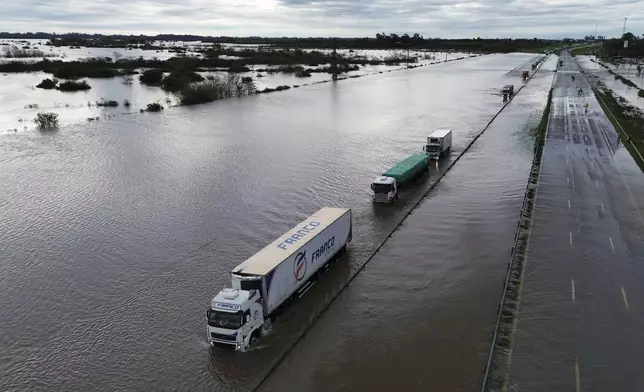 Semi-trucks drive through a flooded highway after heavy rains in Campana, Argentina, Saturday, May 17, 2025. (AP Photo/Rodrigo Abd)