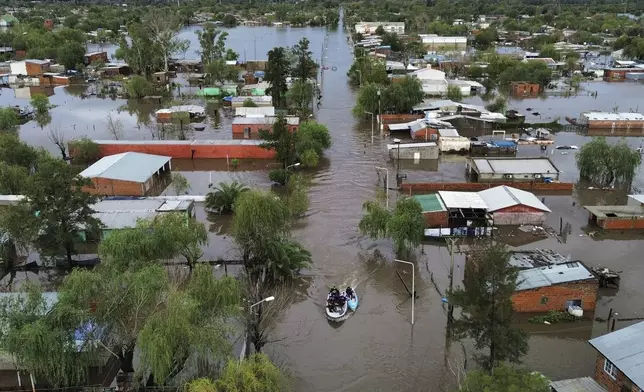 Boats move through flooded streets after heavy rains in Campana, Argentina, Saturday, May 17, 2025. (AP Photo/Rodrigo Abd)