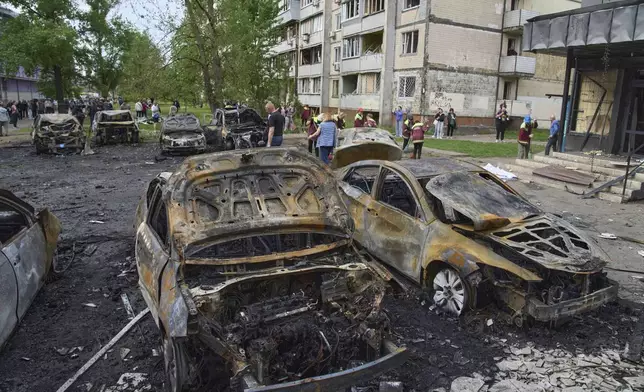Municipal workers clean up burnt cars in the residential area following Russia's drone attack in Kyiv, Ukraine, Sunday, May 4, 2025. (AP Photo/Efrem Lukatsky)