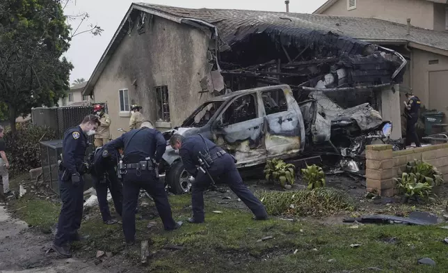 Authorities work the scene where a small plane crashed into a San Diego neighborhood, setting several homes on fire and forcing evacuations along several blocks early Thursday, May 22, 2025. (AP Photo/Gregory Bull)
