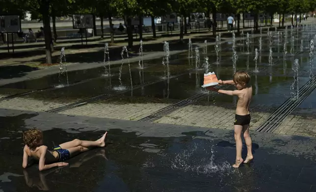Children cool themselves by a fountain at Muzeon park in Moscow, Russia, Thursday, May 22, 2025. (AP Photo/Pavel Bednyakov)