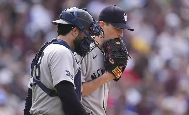 New York Yankees catcher Austin Wells, left, confers with starting pitcher Max Fried, right, after Fried gave up an RBI triple to Colorado Rockies' Michael Toglia in the fourth inning of a baseball game Saturday, May 24, 2025, in Denver. (AP Photo/David Zalubowski)