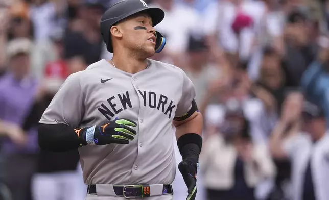 New York Yankees' Aaron Judge heads back to the dugout after touching home plate following his solo home run off Colorado Rockies starting pitcher Kyle Freeland in the first inning of a baseball game Saturday, May 24, 2025, in Denver. (AP Photo/David Zalubowski)