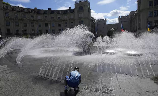 A soccer fan cools off on a fountain ahead of the Champions League final soccer match between Paris Saint-Germain and Inter Milan in Munich, Germany, Friday, May 30, 2025. (AP Photo/Luca Bruno)