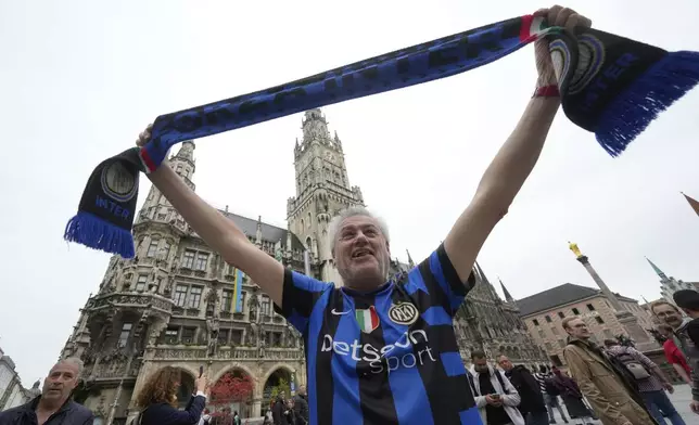 Inter Milan fan Andrea Trebbi holds up a team scarf in front of the Neues Rathaus Town Hall, Thursday, May 29, 2025, ahead of the Champions League final soccer match between Paris Saint-Germain and Inter Milan in Munich, Germany. (AP Photo/Luca Bruno)