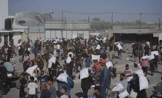 Palestinians carry bags of flour after storming a U.N. World Food Program warehouse in Zawaida, Central Gaza Strip, on Wednesday, May 28, 2025. (AP Photo/Abdel Kareem Hana)