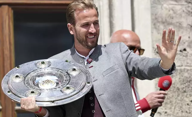Bayern's Harry Kane stands with the championship trophy on the town hall balcony, at the championship celebration in Munich, Germany, Sunday, May 18, 2025. (Daniel Loeb/dpa via AP)