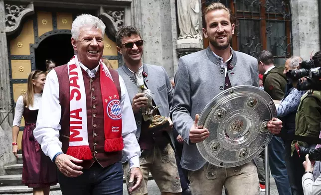Bayern's Harry Kane, right, arrives with the Championship trophy together with teammate Thomas Mueller, center, and Dieter Reiter (SPD), Lord Mayor of Munich, at the championship celebration in the city hall in Munich, Germany, Sunday, May 18, 2025. (Daniel Loeb/dpa via AP)
