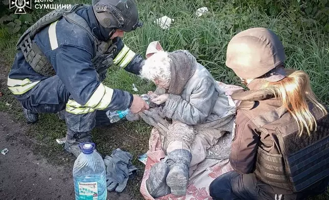 In this photo provided by the Ukrainian Emergency Services on May 8, 2025, a rescue worker helps an injured elderly woman evacuated from a building which was heavily damaged by a Russian strike in Sumy region, Ukraine. (Ukrainian Emergency Service via AP)