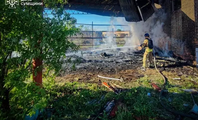 In this photo provided by the Ukrainian Emergency Services on May 8, 2025, a rescue worker puts out a fire of a building which was heavily damaged by a Russian strike in Sumy region, Ukraine. (Ukrainian Emergency Service via AP)