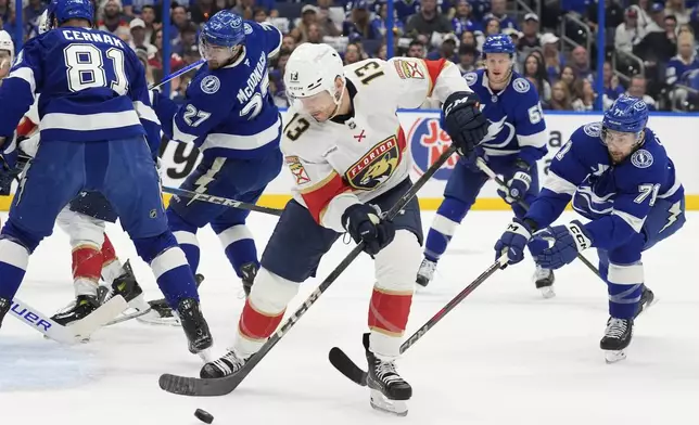 Florida Panthers center Sam Reinhart (13) tries to control the puck between Tampa Bay Lightning defenseman Erik Cernak (81) and center Anthony Cirelli (71) during the first period in Game 5 of an NHL hockey Stanley Cup first-round playoff series, Wednesday, April 30, 2025, in Tampa, Fla. (AP Photo/Chris O'Meara)