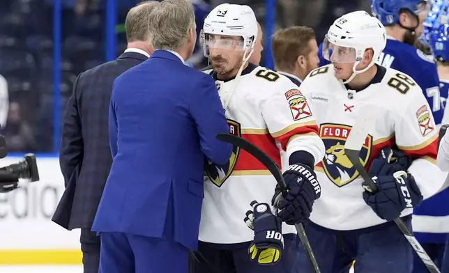 Florida Panthers center Brad Marchand (63) hugs against the Tampa Bay Lightning head coach Jon Cooper after Game 5 of an NHL hockey Stanley Cup first-round playoff series, Wednesday, April 30, 2025, in Tampa, Fla. (AP Photo/Chris O'Meara)