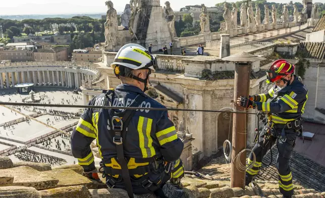 In this image taken on Friday, May 2, 2025, and made available Saturday, May 3, 2025, by Vatican Media, Italian firefighters install a temporary chimney on the roof of the Sistine Chapel at the Vatican, which will release smoke signals—black or white—from the upcoming conclave starting May 7, indicating whether a new pope has been elected. (Vatican Media via AP)