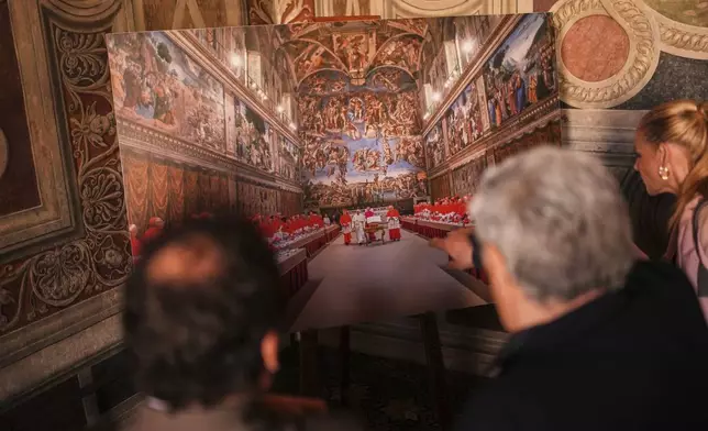 Journalists look at a photograph of the conclave where late Pope Francis was elected on March 13, 2013, and displayed inside the Borgia Apartments at the Vatican Museums during a press tour, Friday, May 2, 2025. (AP Photo/Francisco Seco)