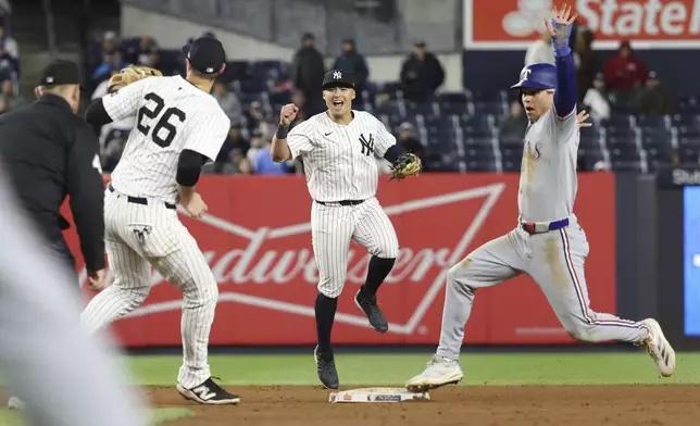 New York Yankees shortstop Anthony Volpe, center, reacts after second baseman DJ LeMahieu, left, tags out Texas Rangers' Sam Haggerty, right, during the ninth inning of a baseball game Wednesday, May 21, 2025, in New York. (AP Photo/Pamela Smith)