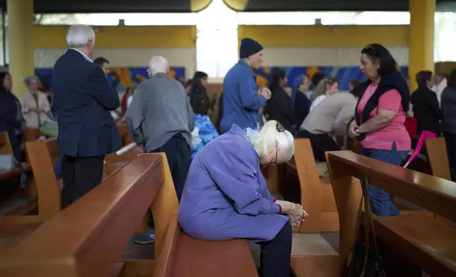 A woman prays during a mass in San Paolo Della Croce parish church in Corviale neighbourhood, in Rome, Sunday, May 4, 2025. (AP Photo/Alessandra Tarantino)