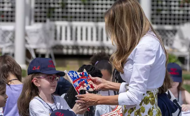 First lady Melania Trump looks at a decorated flag as she participates in flag decorating during a Take Our Child to Work Day event in the Jacqueline Kennedy Garden at the White House, Tuesday, May 20, 2025, in Washington. (AP Photo/Alex Brandon)