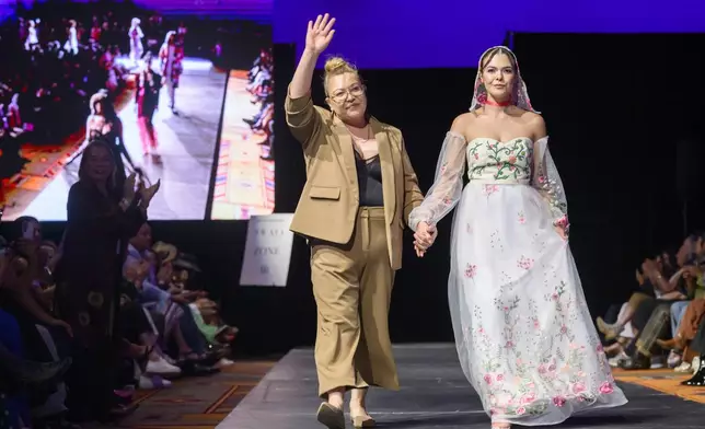 Designer Tishna Marlowe, left, is accompanied by a model wearing one of her designs during the 2025 Native Fashion Show, Friday, May 9, 2025, in Santa Fe, N.M. (AP Photo/Roberto E. Rosales)