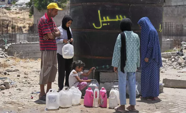 Members of the Abu Jarad family, who were displaced by the Israeli air and ground offensive in the Gaza Strip, fill containers with water in Gaza City, Tuesday, May 20, 2025. (AP Photo/Jehad Alshrafi)