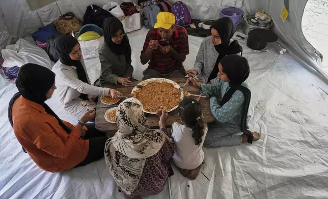 Members of the Abu Jarad family, who were displaced by the Israeli air and ground offensive in the Gaza Strip, eat in a tent where they are sheltering in Gaza City, Tuesday, May 20, 2025. (AP Photo/Jehad Alshrafi)