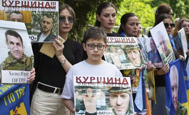 Family members of Ukrainian prisoners hold banners and photos of servicemen in captivity ahead of an exchange of prisoners between Russia and Ukraine, in Chernyhiv region, Ukraine, Friday, May 23, 2025. (AP Photo/Efrem Lukatsky)