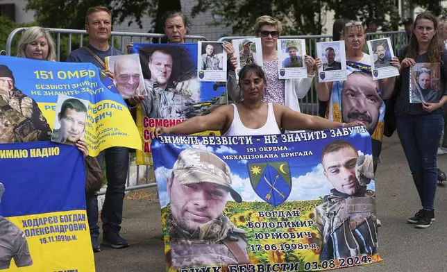 Family members of Ukrainian prisoners hold banners and photos of servicemen in captivity ahead of an exchange of prisoners between Russia and Ukraine, in Chernyhiv region, Ukraine, Friday, May 23, 2025. (AP Photo/Efrem Lukatsky)