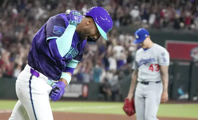 Arizona Diamondbacks outfielder Lourdes Gurriel Jr., left, pumps is fist after hitting a grand slam off of Los Angeles Dodgers pitcher Anthony Banda, right, during the fifth inning of a baseball game Friday, May 9, 2025, in Phoenix. (AP Photo/Darryl Webb)