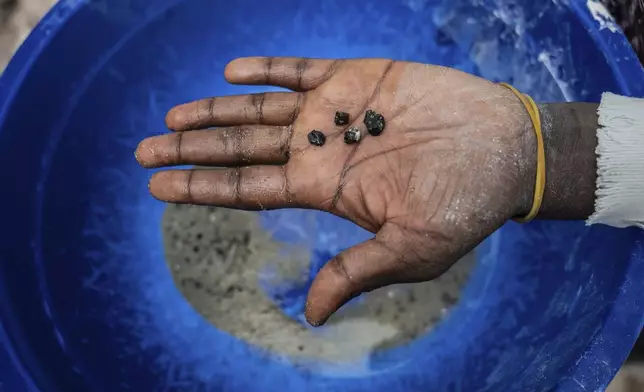 A mine worker holds bits of coltan ore in the mining town of Rubaya, Democratic Republic of Congo, on Friday, May 9, 2025. (AP Photo/Moses Sawasawa)