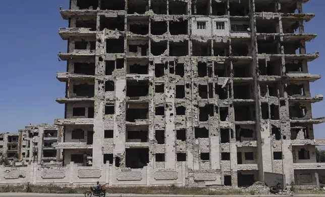 A restored apartment, top center, can be seen in an otherwise severely damaged apartment building in the Al-Waer neighborhood of Homs, Syria, Tuesday, May 13, 2025. (AP Photo/Ghaith Alsayed)